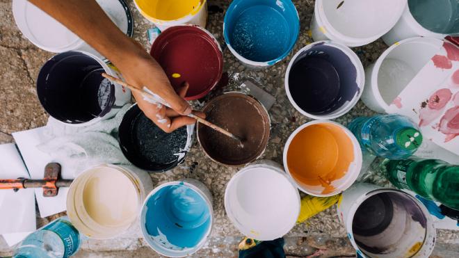 Open paint buckets in many colors seen from above
